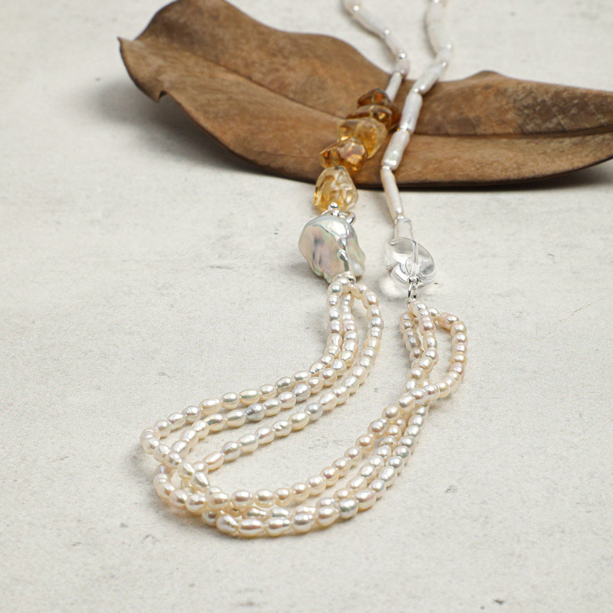 Pearl necklace with gold clasp on a textured surface