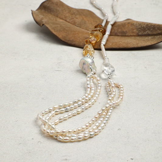 Pearl necklace with gold clasp on a textured surface